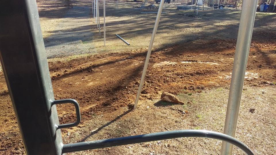 View from equipment cab of freshly graded red clay soil over a completed septic line at a residential job site.