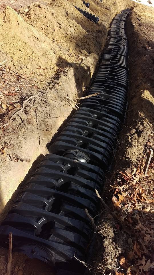 Black plastic infiltrator septic chambers laid in a dirt trench for a leach field installation